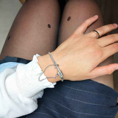 Bracelet fin argenté avec chaîne et fermoir en cœur porté sur poignet féminin, style délicat et moderne.