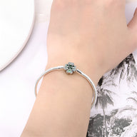 Bracelet fin en argent avec charm trèfle à quatre feuilles sur poignet féminin.