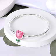 Bracelet argenté serpent avec breloque tulipe rose en émail et détail feuillage vert.