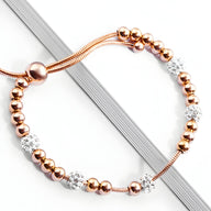 Bracelet femme en titane or rosé avec perles lisses et boules serties de zircones blanches scintillantes.