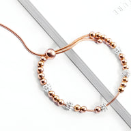 Bracelet femme en titane or rosé avec perles métalliques et zircones blanches scintillantes.