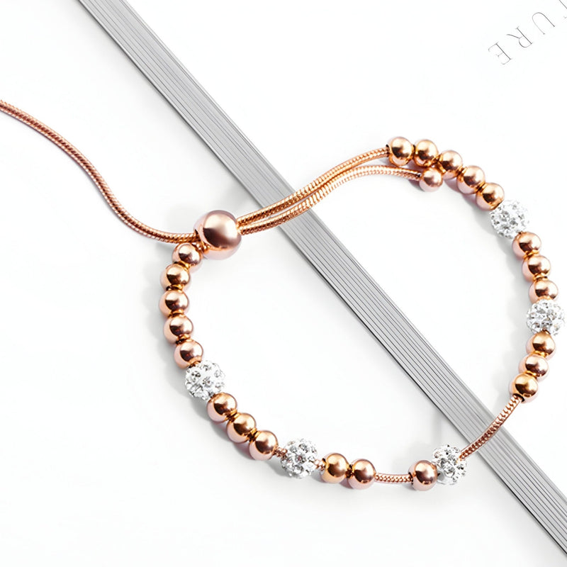 Bracelet femme en titane or rosé avec perles métalliques et zircones blanches scintillantes.