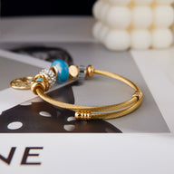 Bracelet doré pour femme en acier inoxydable avec arbre de vie et charms colorés turquoise et dorés.
