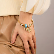 Bracelet or pour femme en acier inoxydable avec arbre de vie et plusieurs breloques colorées.