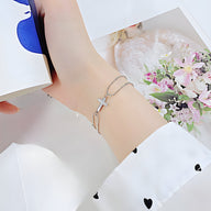 Bracelet femme en acier inoxydable argenté avec charm croix délicate et chaîne fine.