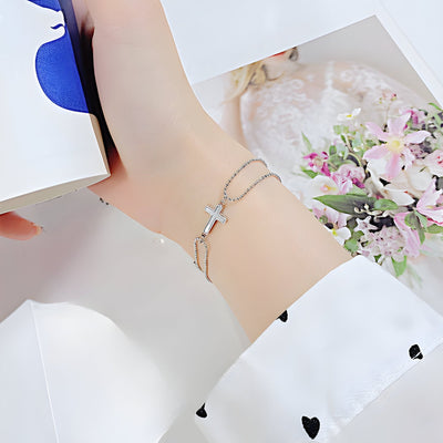 Bracelet femme en acier inoxydable argenté avec charm croix délicate et chaîne fine.