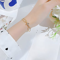 Bracelet femme chaîne fine en acier inoxydable doré avec charm croix ajourée élégante.