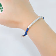 Bracelet pour femme à cordon bleu avec plaque métallique argentée lisse et ajustable.