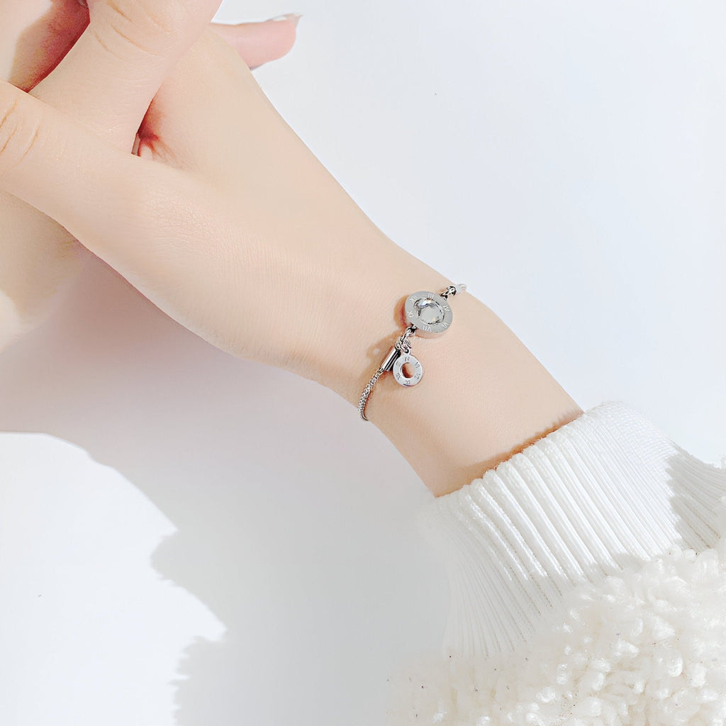 Bracelet femme en acier argenté avec charms chiffres romains en verre, style élégant et délicat.