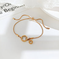 Bracelet pour femme en acier inoxydable or rosé avec charm chiffres romains en verre transparent.