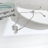 Bracelet femme en acier inoxydable argenté avec charm chiffres romains en verre et fermoir coulissant.