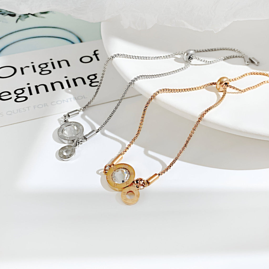 Bracelet femme en acier inoxydable or rosé avec charms chiffres romains en verre et réglage coulissant, modèle Nika.