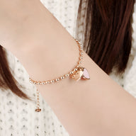 Bracelet femme en acier inoxydable or rosé avec chaîne à billes et charme double cœur lisse et ajouré.