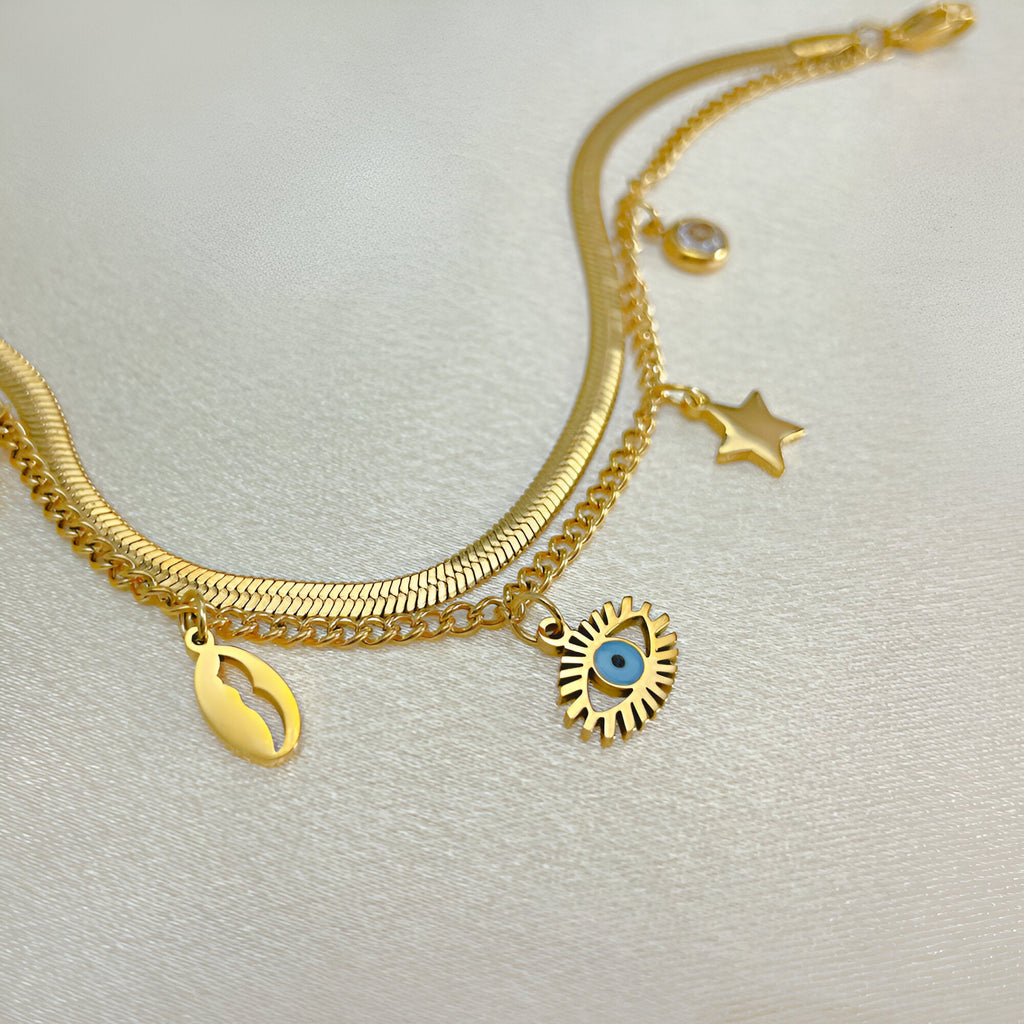 Bracelet femme or en acier inoxydable avec charms œil bleu, étoile et coquillage nacré.