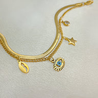 Bracelet femme or en acier inoxydable avec charms œil bleu, étoile et coquillage nacré.