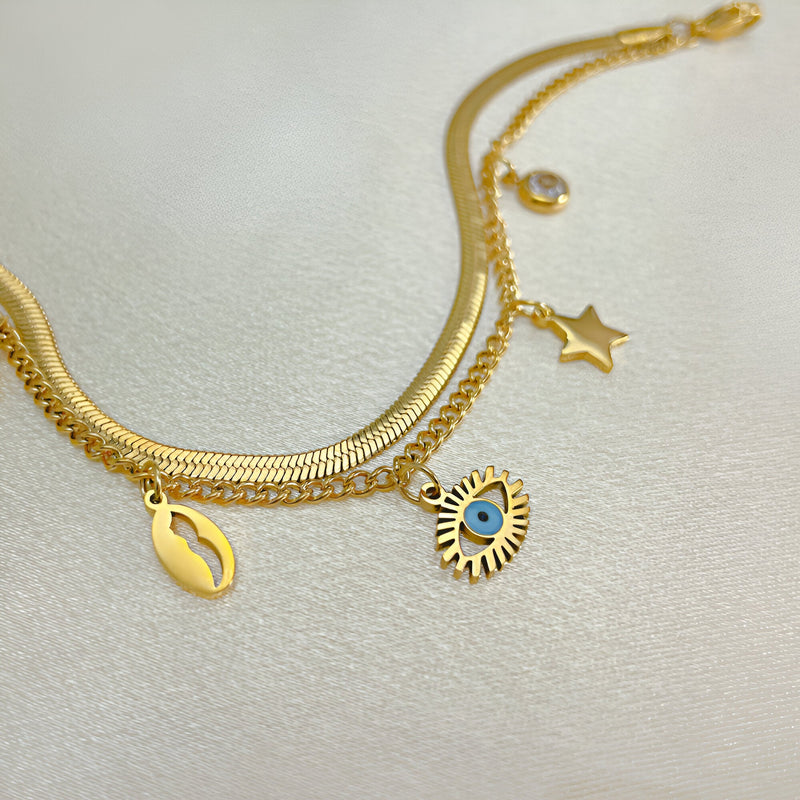 Bracelet femme or en acier inoxydable avec charms œil bleu, étoile et coquillage nacré.