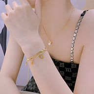 Bracelet fin en acier inoxydable doré avec charms œil et étoile, porté au poignet féminin.