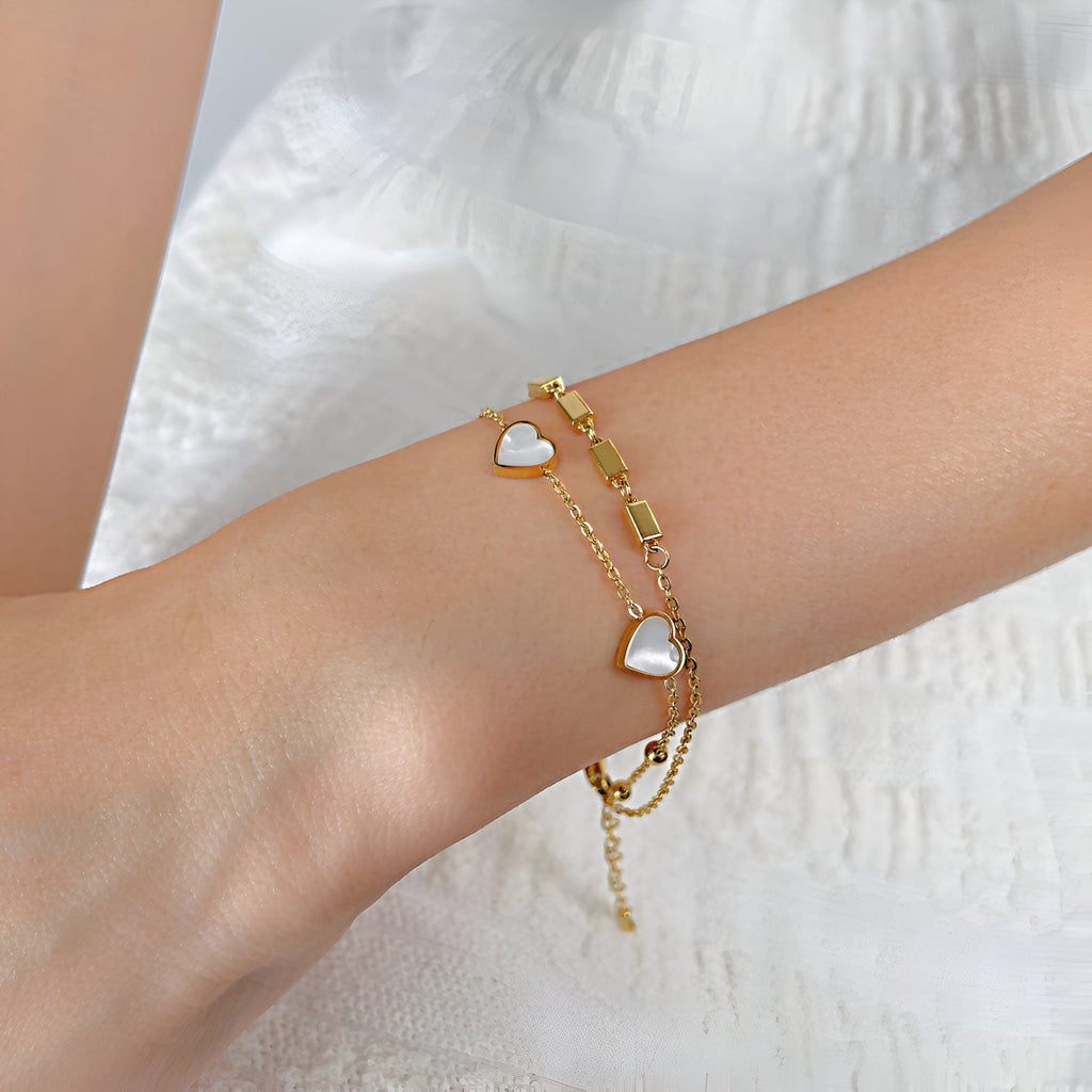 Bracelet or en acier inoxydable avec chaînette double et cœurs ornés de zirconium blanc.