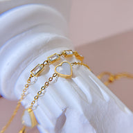 Bracelet or en acier inoxydable avec pendentifs cœurs et zirconium sur chaîne fine délicate.