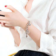 Bracelet argenté en acier inoxydable avec pendentifs cœurs et arbre de vie, style chaîne fine.