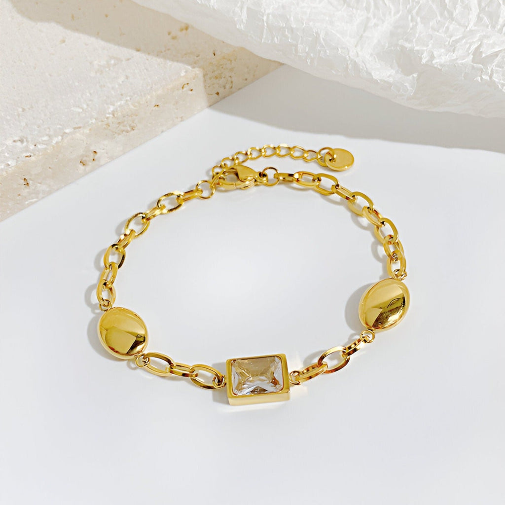 Bracelet femme en acier inoxydable doré avec cube de zirconium scintillant et maillons ovales larges.