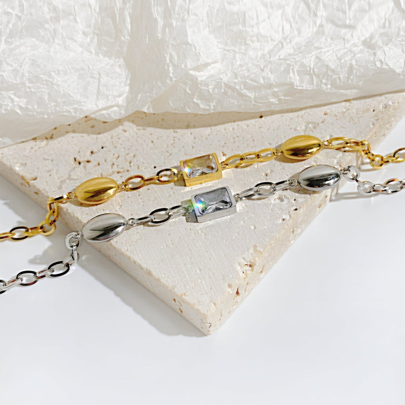 Bracelet femme en acier inoxydable or et argent avec cube de zirconium scintillant.