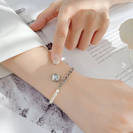 Bracelet femme en acier inoxydable argenté avec perles blanches et charm smiley rond.