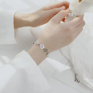 Bracelet femme en acier inoxydable argenté avec plusieurs pendentifs arbres de vie ronds et chaînette fine.