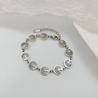 Bracelet femme en acier inoxydable argenté à pendentifs disques avec arbres de vie gravés.