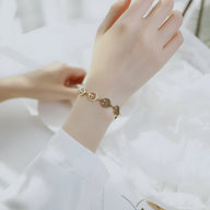 Bracelet femme en acier inoxydable doré avec multiples pendentifs arbres de vie circulaires.