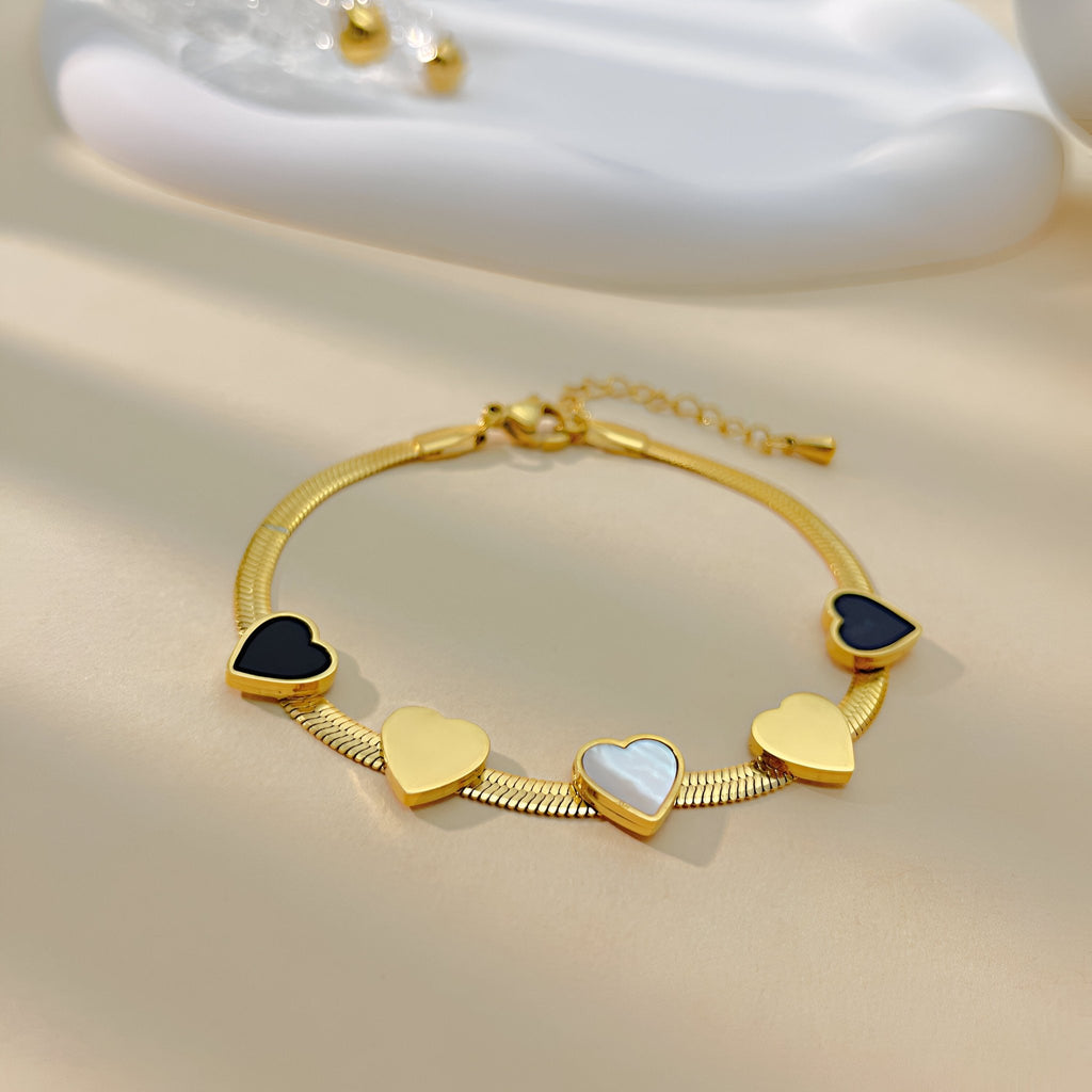 Bracelet femme or en acier inoxydable avec multiple cœurs noirs, blancs et dorés, modèle Keira.