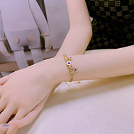 Bracelet femme en acier inoxydable doré avec pendentif œil violet et chaîne fine ajustable.