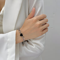 Bracelet femme en acier inoxydable doré avec pendentif cœur noir et chaînes élégantes.