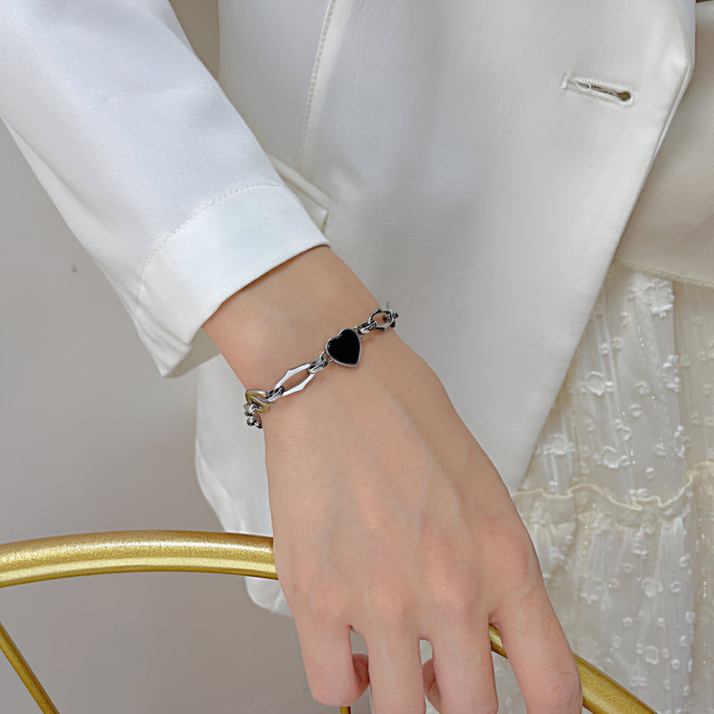 Bracelet en acier inoxydable argenté avec cœur noir brillant, style délicat et moderne.