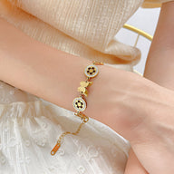 Bracelet femme en acier inoxydable doré avec papillon et fleurs délicates sur chaîne fine.
