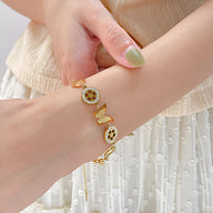 Bracelet femme en acier inoxydable doré avec papillon et pendentifs fleurs détaillés.