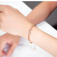 Bracelet femme en acier inoxydable doré avec perles et motif infini ajustable.