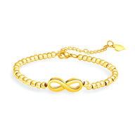 Bracelet femme en acier inoxydable doré avec perles fines et motif infini central lisse.