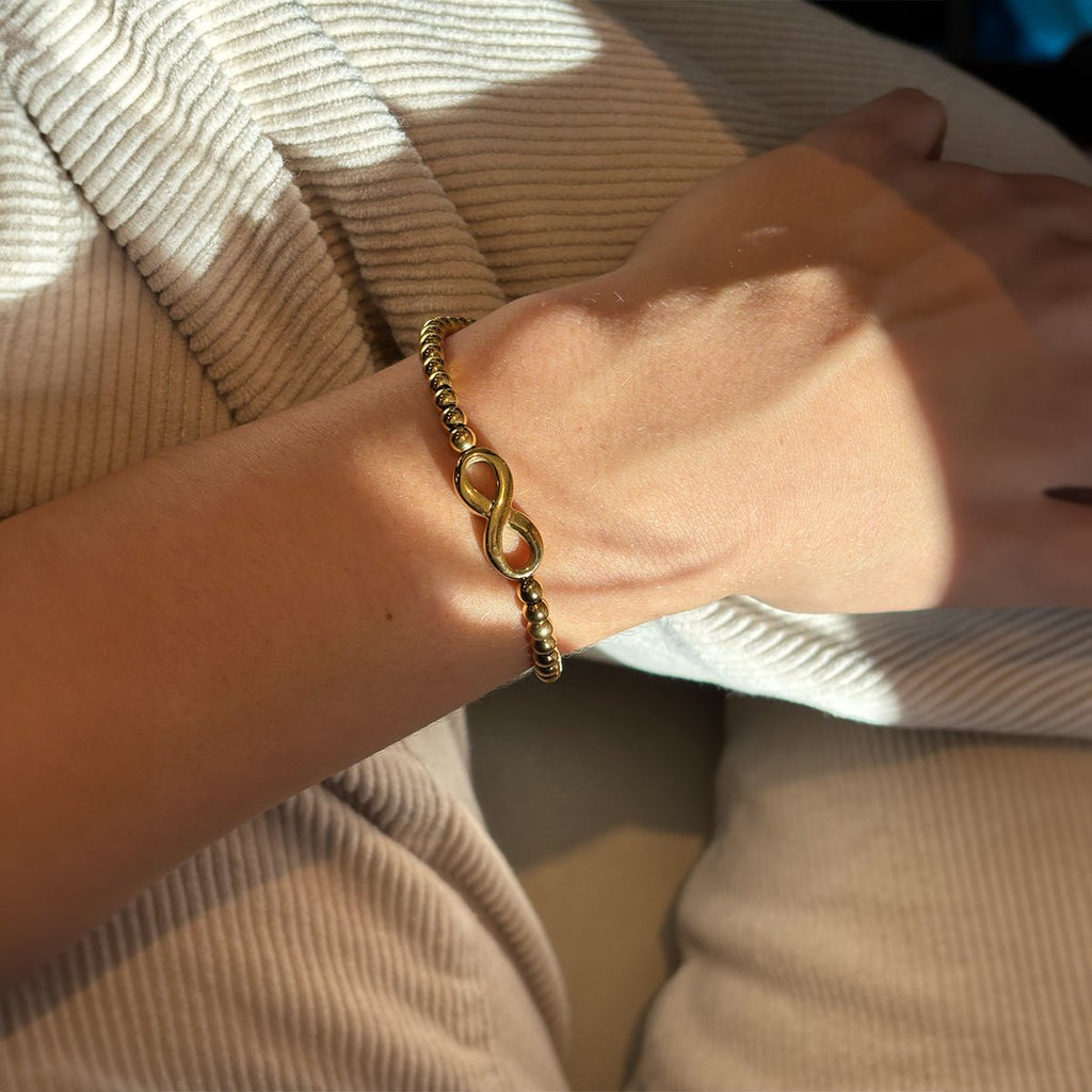 Bracelet fin en acier inoxydable doré avec motif infini et perles délicates, modèle Esther.