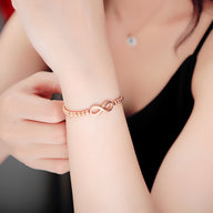 Bracelet femme en acier inoxydable doré, perles fines et motif infini central élégant.