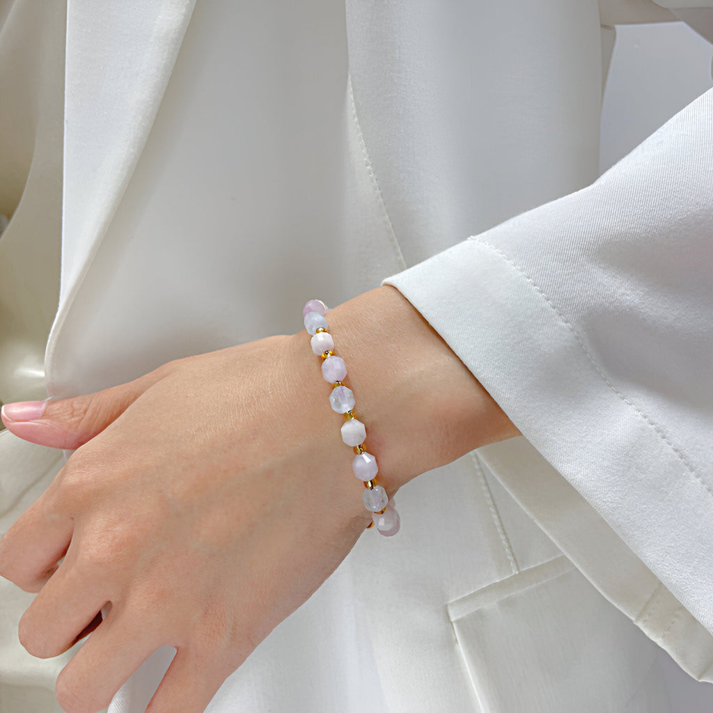 Bracelet en acier inoxydable doré avec pierres roses de morganite sur poignet féminin.