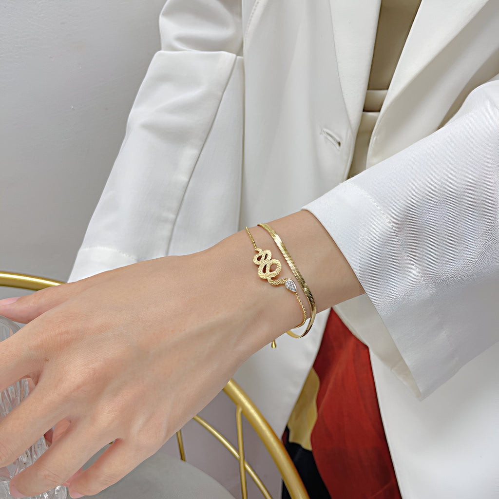 Bracelet serpentin en acier inoxydable doré, design glissant et fin, porté au poignet féminin.