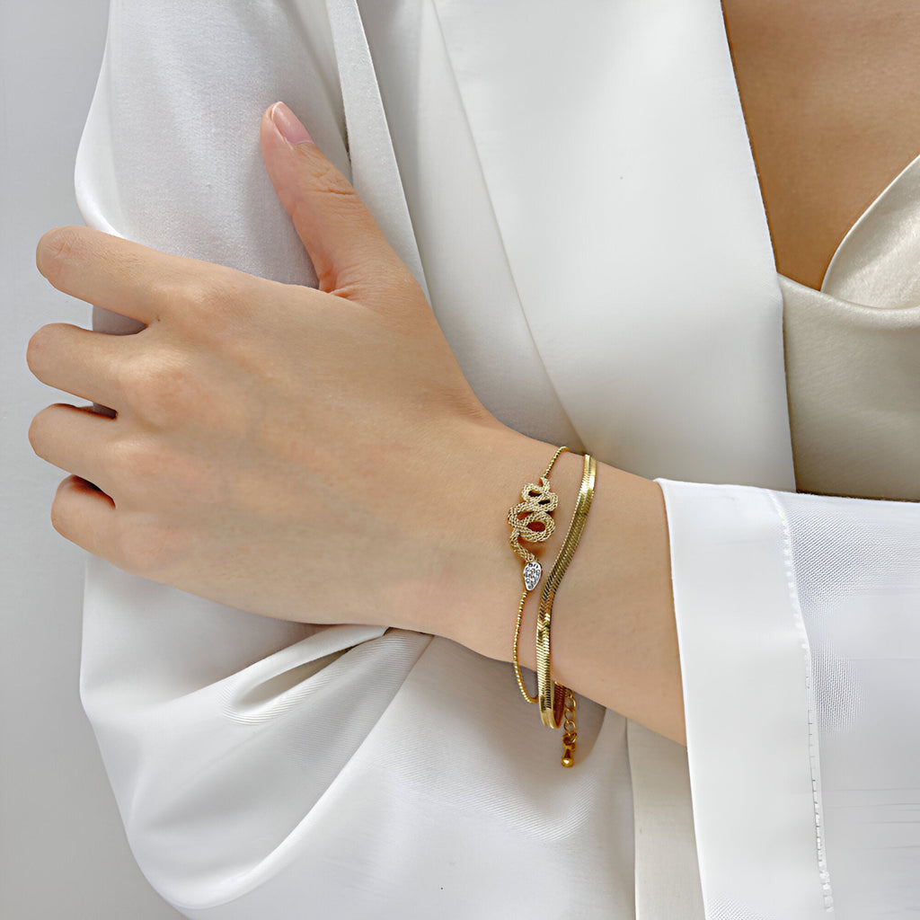 Bracelet serpent glissant en acier inoxydable doré, design fin et élégant, porté au poignet féminin.