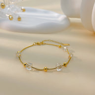 Bracelet fin en acier inoxydable doré avec cubes d'oxyde de zirconium et perles dorées élégantes.