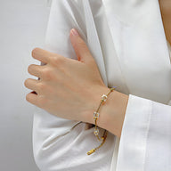 Bracelet fin en acier inoxydable doré avec cubes d'oxyde de zirconium sertis sur poignet féminin habillé d'une chemise.