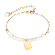 Bracelet femme en acier inoxydable or orné de perles blanches et médaille rectangulaire gravée.