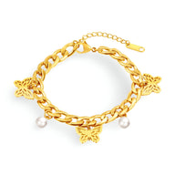 Bracelet femme en acier inoxydable doré avec chaîne épaisse, trois papillons sculptés et deux perles blanches suspendues.