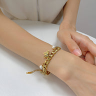 Bracelet femme en acier inoxydable doré avec trois papillons sculptés et perle sur chaîne élégante.