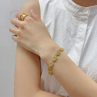 Bracelet fin en cuivre doré orné de multiples papillons sertis de zirconium sur poignet féminin.