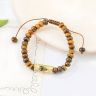 Bracelet femme en perles d’œil de tigre marron avec pendentif main égyptienne doré et cordon réglable.